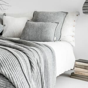 Kissen Cosy von Moyha moderner Strick auf dem Bett drapiert in Grau weiss Boho Alpenstyle